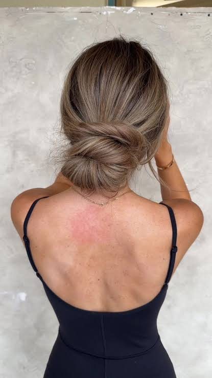A soft, low bun sits away from the hairline