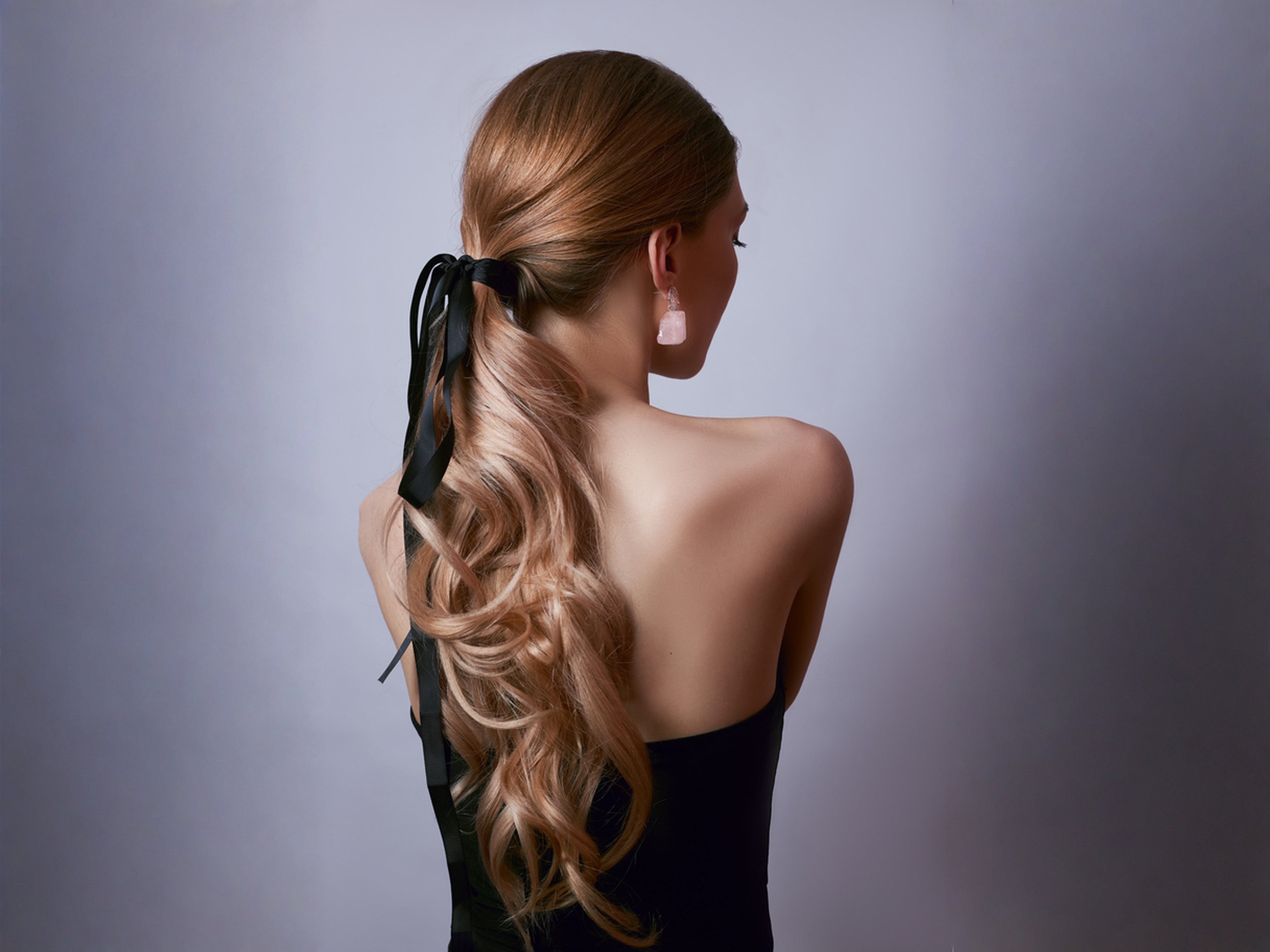 Image placeholder: an elevated low ponytail with a soft crown, smooth sides, and a polished low tie.
